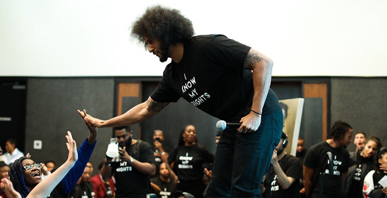 Colin Kaepernick high fiving people in audience